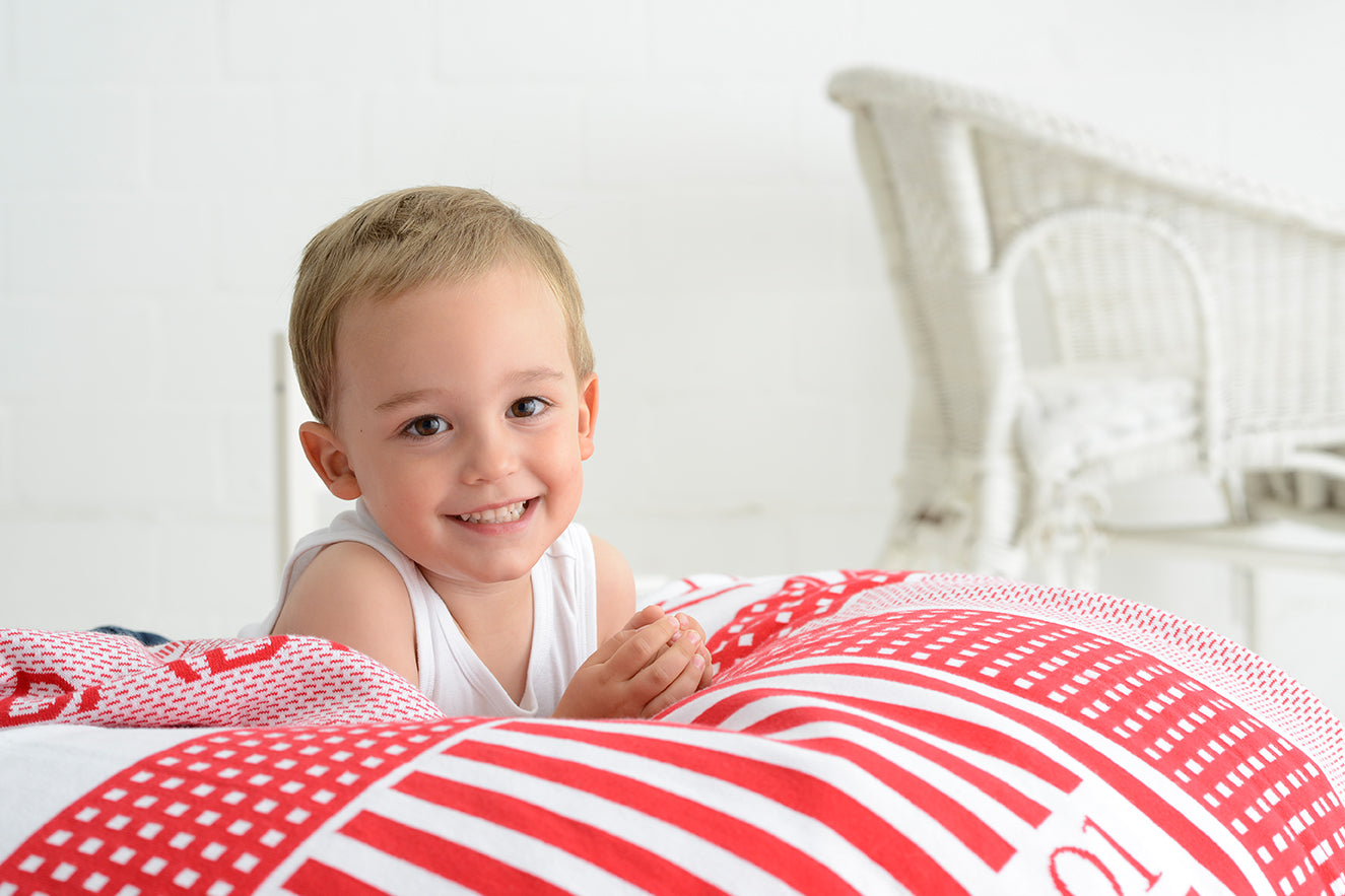 Bio Kuscheldecke XL GEKROENT mit Namen in Rot beim Fotoshooting mit Moritz